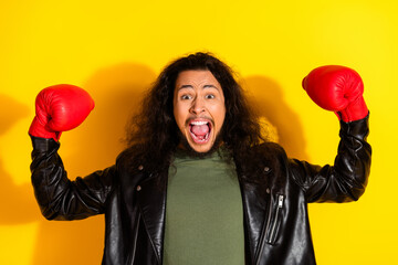 Energetic young man with long hair and a black leather jacket enthusiastically posing with red...