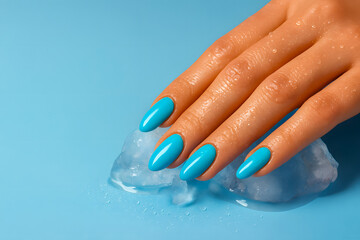 Well-manicured hand with bright blue nail polish rests on ice cubes on a light blue surface, displaying elegance and refreshing aesthetics through the bold and clean presentation.