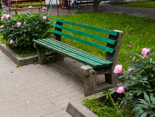 A green park bench sitting in the middle of a flower garden