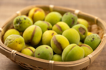 竹かごに痛みや斑点のある青梅のアップ