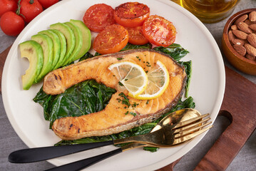 Grilled salmon fish fillet and fresh green lettuce vegetable tomato salad with avocado guacamole. Balanced nutrition concept for clean eating flexitarian mediterranean diet.