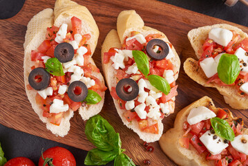 Bruschetta with tomatoes, mozzarella cheese and basil on a cutting board. Traditional italian...