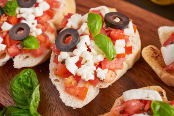 Bruschetta with tomatoes, mozzarella cheese and basil on a cutting board. Traditional italian appetizer or snack, antipasto. Caprese salad bruschetta. Top view with copy space. Flat lay.