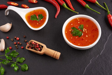 
red hot chilli sauce. tomato ketchup, chilli sauce, puree with chili pepper, Vegetables, tomatoes and garlic. on on black stone background. top view
