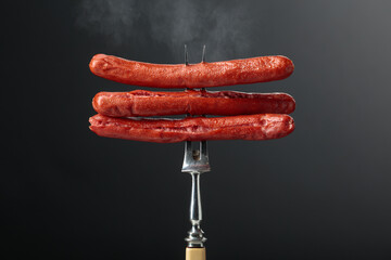 Thin grilled sausages on a fork.