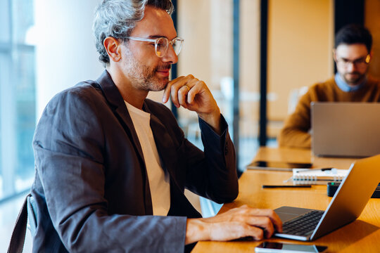 Man working on laptop at a desk in a bright office