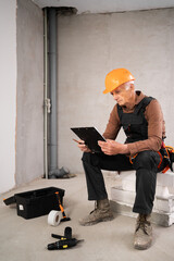 Civil engineer elderly man with clipboard reading checklist making inspection notes working at construction site. Repair, renovation and construction