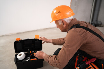 Elderly civil engineer or builder opening toolbox making house repair working on home interior design