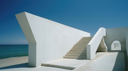 Modernist concrete structure with geometric shadows overlooking a calm ocean under clear blue sky