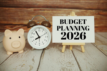 Budget Planning 2026 text message with alarm clock and piggy saving on wooden background