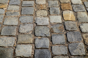 Close-up of an old cobblestone pavement with uneven surface and natural color variations.