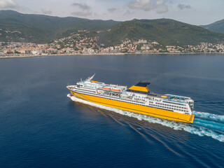 Big yellow passenger ferry goes on the Mediterranean Sea near Corsica island, France aerial view Cityscape Bastia port