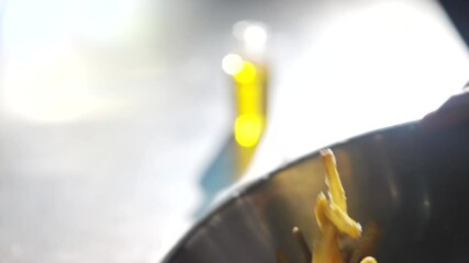 A person is holding a bowl of food, which appears to be a mix of fries and other ingredients. The bowl is filled with a variety of food items, including some that look like french fries