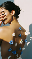 Woman's back adorned with blue and white flowers, a minimalist beauty concept.