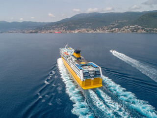 Big yellow passenger ferry goes on the Mediterranean Sea near Corsica island, France aerial view Cityscape Bastia port