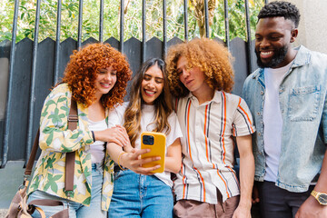 Multiethnic group of young friends smiling, bonding over smartphone, displaying genuine camaraderie and shared joy in casual social interaction