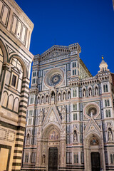 Fototapeta premium People gather at outdoor tables in front of the illuminated Florence Cathedral and Baptistery at night