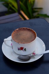  Enjoy a rich, inviting cup of coffee, perfectly presented in a charming floral mug on a dark table. Ideal for cozy moments and relaxation. 
