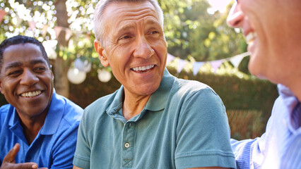 Close Up Of Smiling Mature Male Friends Socializing In Backyard Together