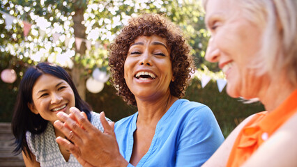 Close Up Of Smiling Mature Female Friends Socializing In Backyard Together