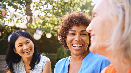 Close Up Of Smiling Mature Female Friends Socializing In Backyard Together