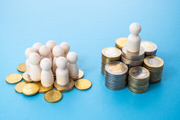 Wooden figures, on piles of coins, concept of wealth distribution. Few people hold most of the...