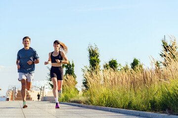 Friends Enjoy a Sunny Morning Jog Along a Scenic Pathway Surrounded by Lush Greenery and Bright...
