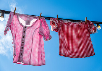 Colorful clothes drying on a line amidst lush green grass in a rural area during bright daytime