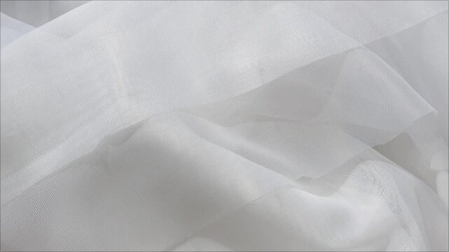 Waves on white tulle for the window. Light textured fabric background. Curtains for the window frame.