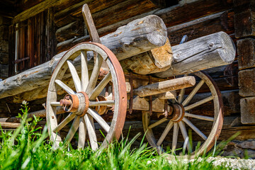 Vintage wooden cart with large wheels resting on a dusty floor in a rustic barn environment during the late afternoon light