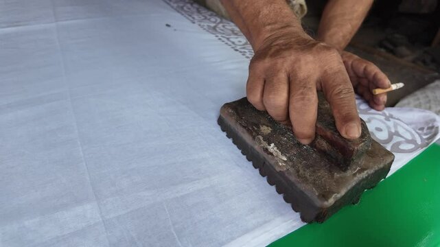 Bangladeshi man stamping wax on a cloth in a batik factory, Comilla, Bangladesh