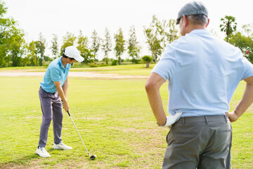 Asian man and elderly father are enjoy playing golf together with a good time.