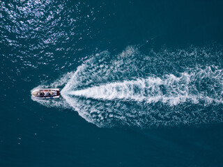 Aerial view of a jet ski speeding across dark blue water, leaving a dynamic white trail. Captured...