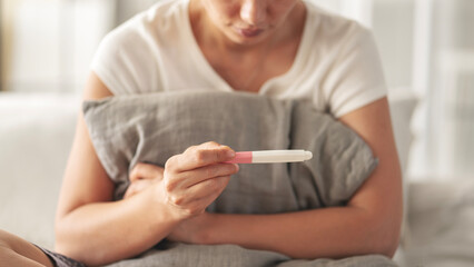 Young woman holding pregnancy test with negative result