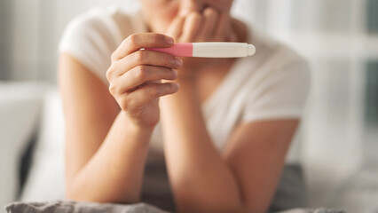 Young woman holding pregnancy test with negative result