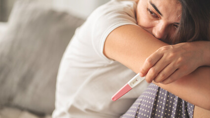 Young woman holding pregnancy test with negative result