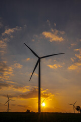 Vertical silhouette wind turbines on sunset in countryside power plant