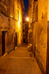 Obraz premium A nighttime view of Pitigliano, a charming Tuscan village perched on cliffs, glowing with warm lights and rich in medieval atmosphere