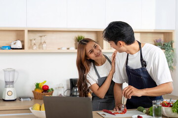 Couple Bonding While Cooking. A playful moment as a woman embraces her partner while he prepares food.