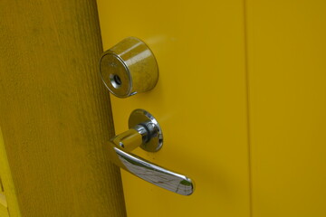 Ordinary everyday things, door accessories, metal strong fittings. Large metal handles, door locks, metal latches are on the new yellow door.