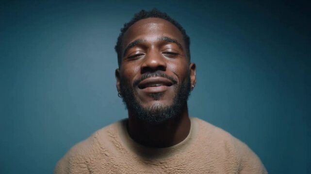 Friendly african american man smiling with open palms raised towards the camera against a blue background, gesturing a welcoming hello or open communication for connection and interaction themes