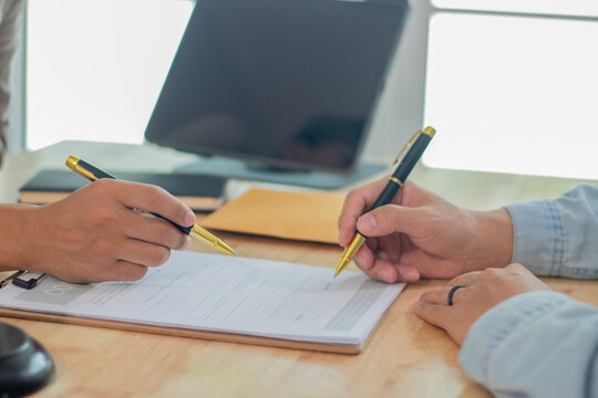 Two experts, a businessman and a lawyer, are discussing legal documents in an office, reviewing contracts, strategies and investment laws during a planning meeting.