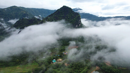 Aerial view of greenery mountains and rural village on foggy morning