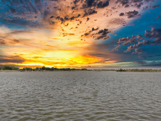 Picture of beautiful sunset over the lake with cloudy sky. Nature composition.
