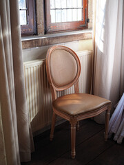 Vintage leather upholstered wooden chair in corner by old window – perfect for interior decor promotion