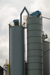 Industrial silos storing cement or other building materials under cloudy sky