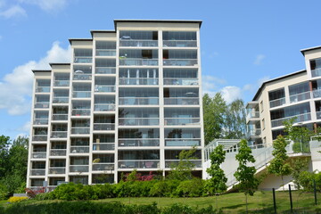 Apartments, houses, real estate located by the sea bay and illuminated by the rays of the sun in Espoo city, Finland. New beautiful white houses with large glass balconies are located among tall green