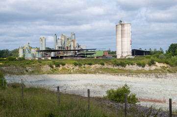 Chalk quarry with processing plant and silos under cloudy sky