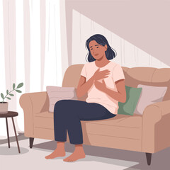  A woman sitting on a sofa holding her chest, feeling discomfort.