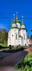 View of the Vydubychi Monastery and green trees in Kiev. A woman walking down the road near Orthodox Christian Church. Kyiv Ukraine. Europe